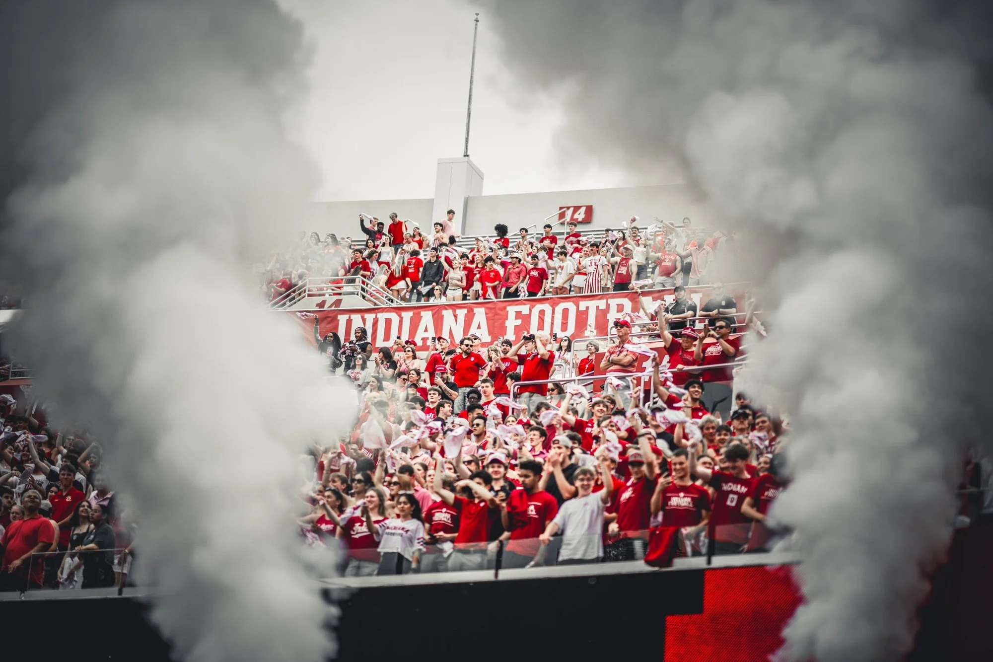 Indiana student section cheering as smoke billows across the stands.