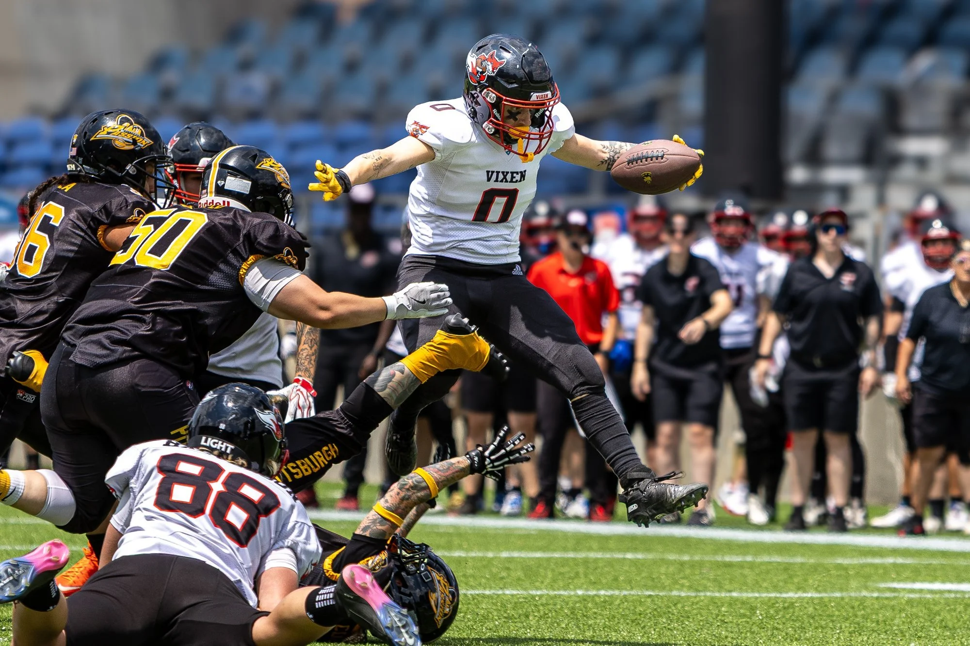 Women's pro football ball carrier hurdles a diving defender in Indiana