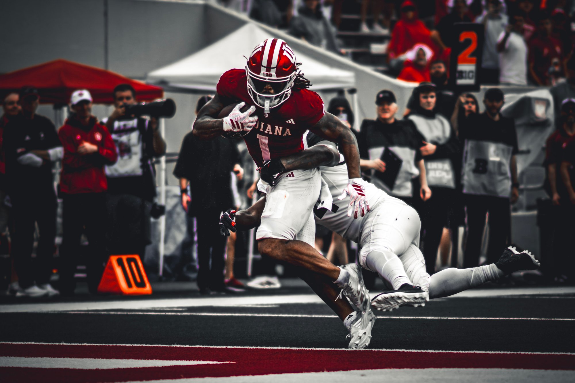 Indiana ball carrier stepping through an attempted tackle near the sideline.