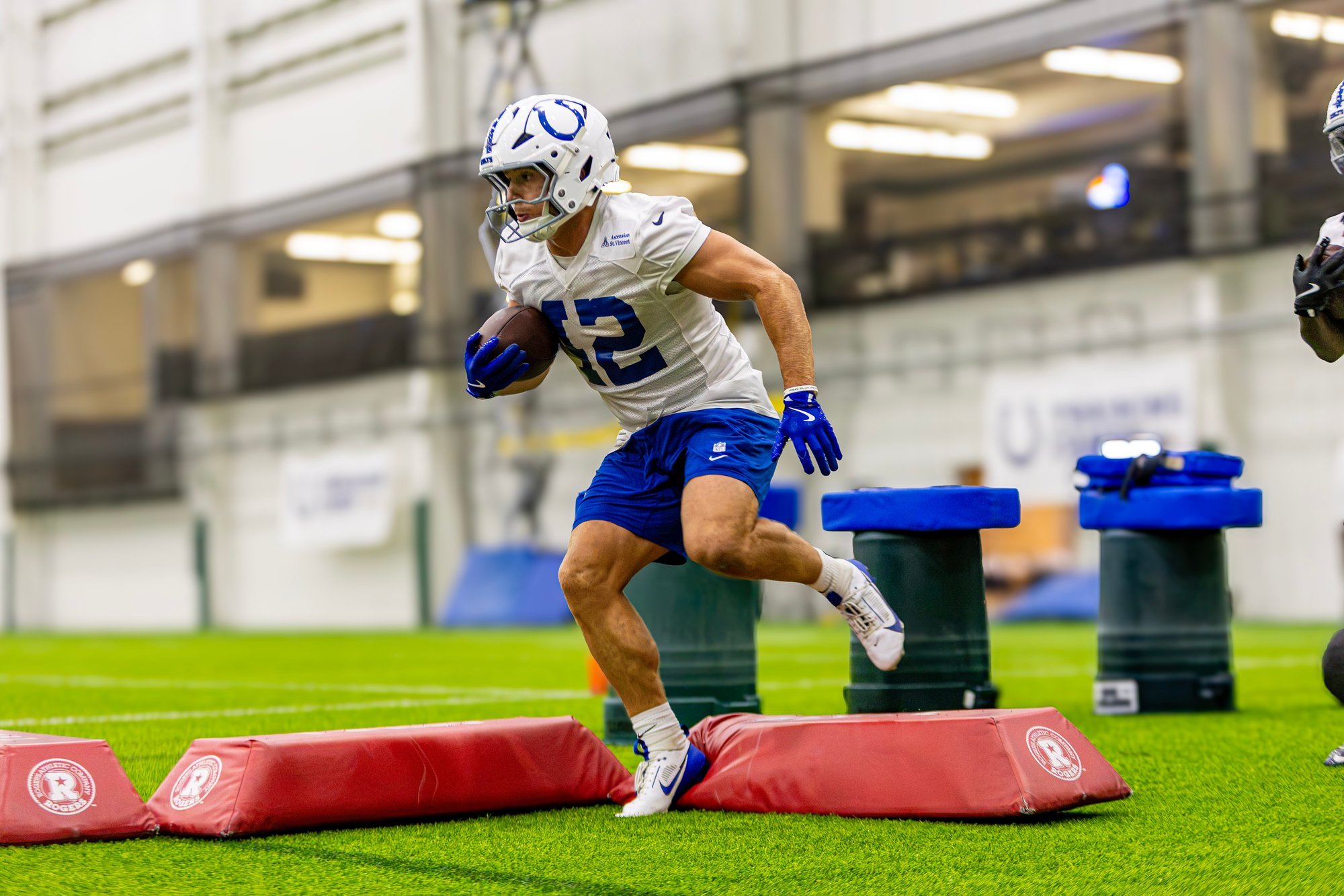 Colts player stepping through agility bags during an indoor training camp drill.