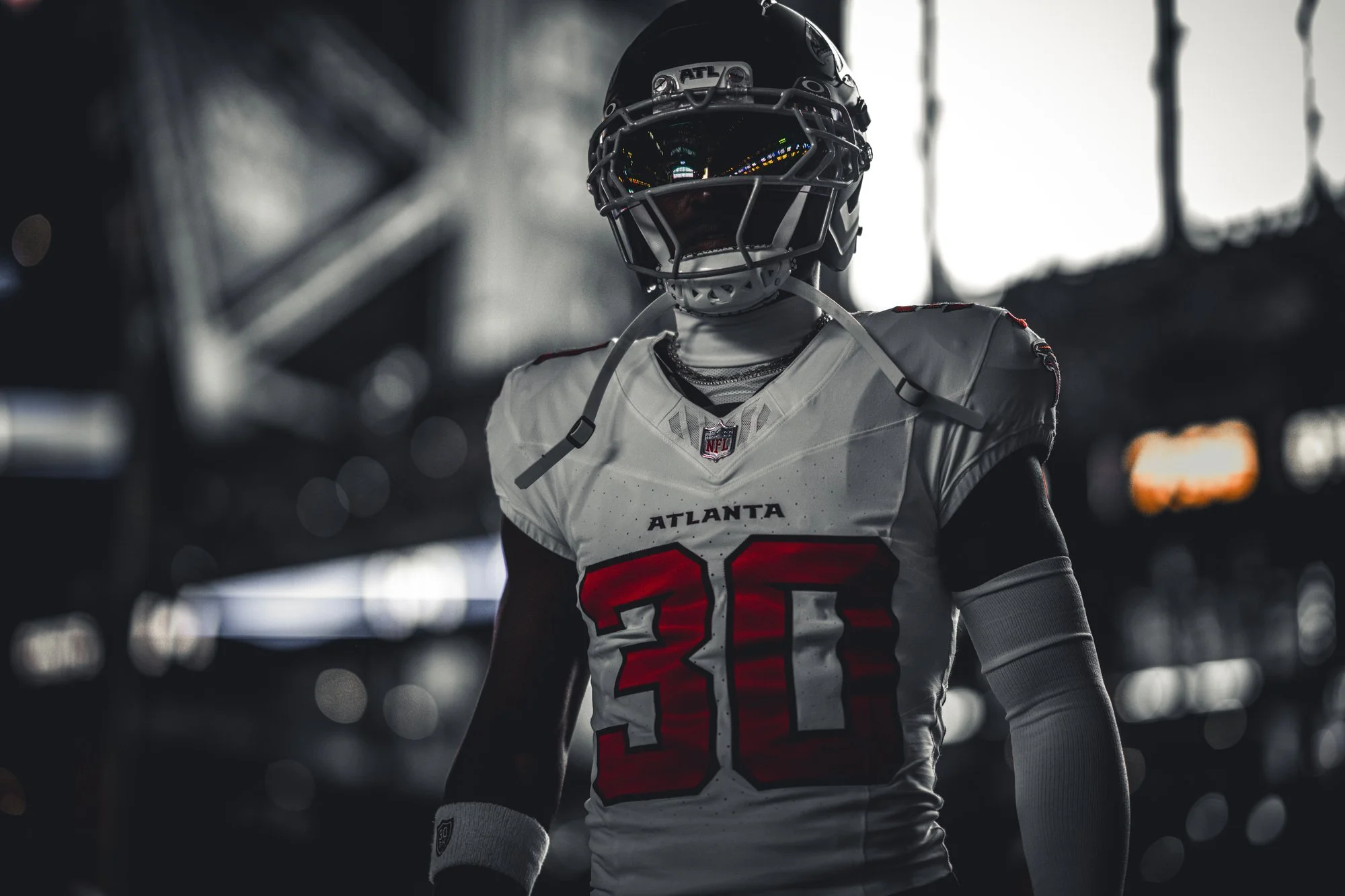 Atlanta Falcons player in a white road jersey standing in dramatic low light.