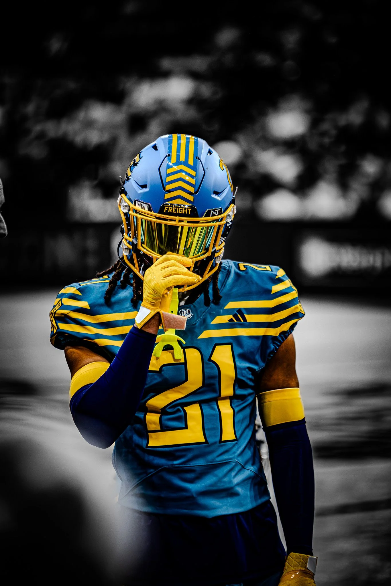Indoor football player #21 in gold-visor helmet on the sideline