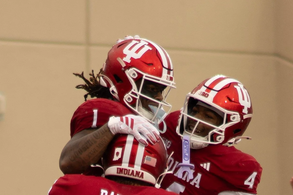 Close-up of two Indiana players in crimson helmets celebrating together.