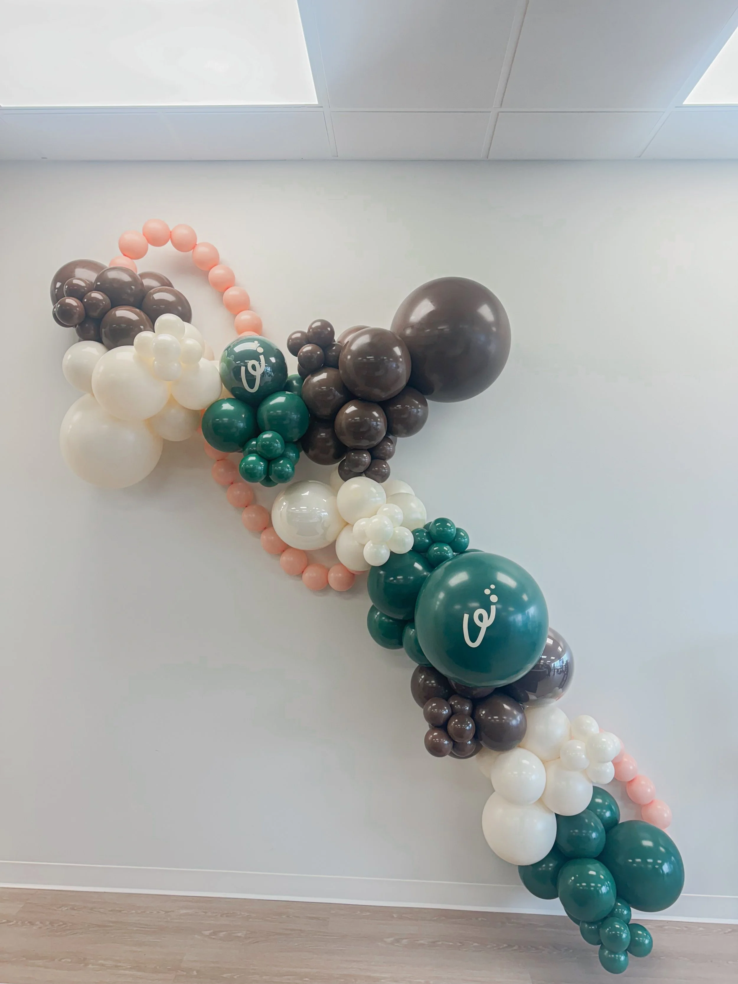 Decorative balloon garland with brown, dark green, and white balloons with a company logo custom placed on balloons