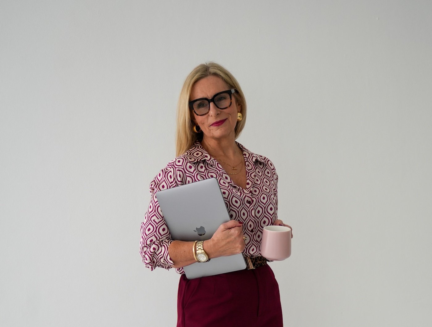 Michelle Cuneo, Central Coast relationship counsellor at Red Thread Relationships, standing with a laptop and coffee, preparing for online therapy session.