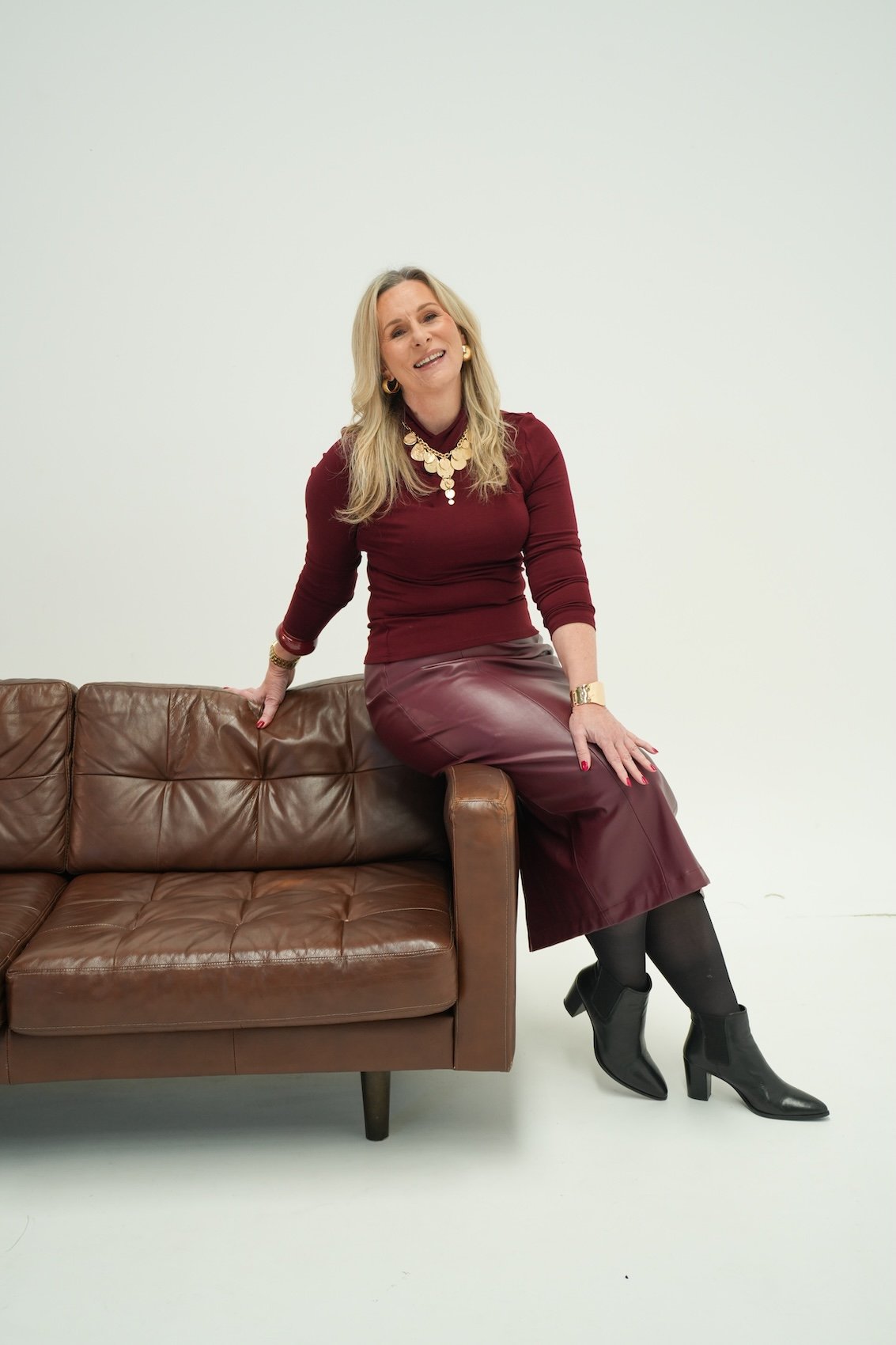 Michelle Cuneo, founder of Red Thread Relationships on the Central Coast, NSW, seated on a brown leather sofa for therapy branding imagery.