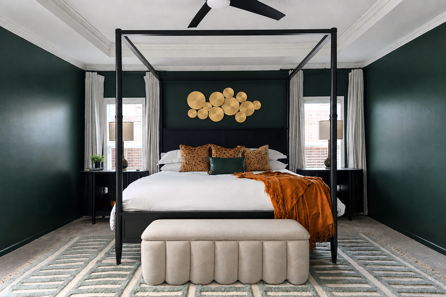 Primary bedroom in a luxury short-term rental, designed by Kelsey Brown Interiors. The bedroom is based in the Dallas-Fort Worth area and includes Essex green walls, a black canopy bed, and burnt orange and gold accents. 