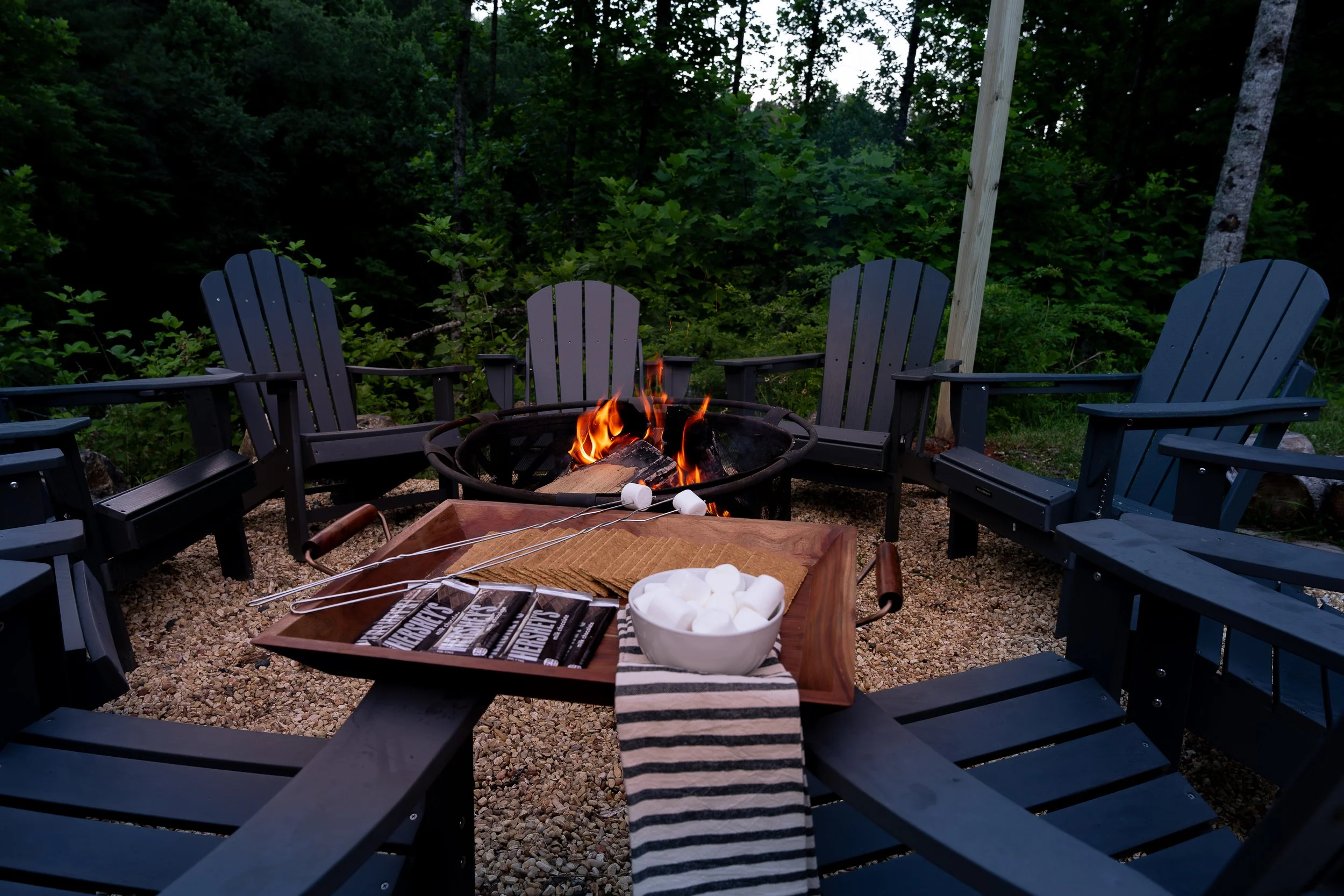 A firepit with black adirondack chairs in Asheville North Carolina, designed by Kelsey Brown Interiors