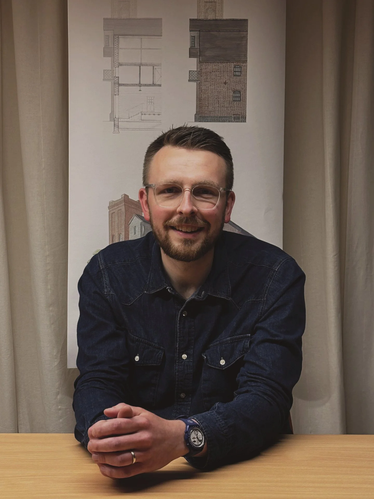 24/three team mamber alex manley sat in the boardroom wearing a navy shirt and smiling at the camera