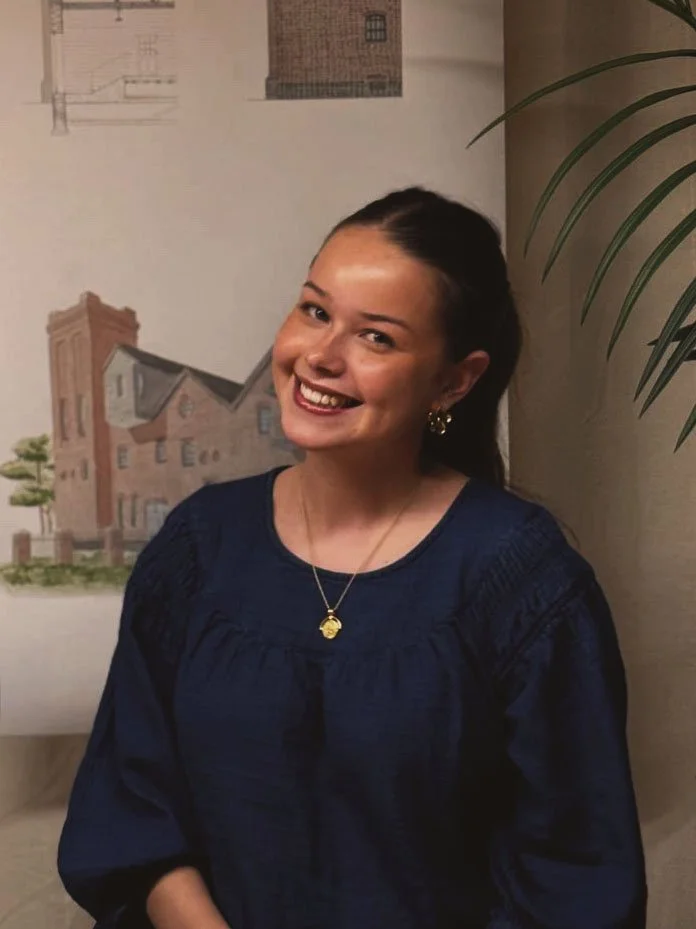 24/Three Poppy, Administrative Assistant, smiling at her desk