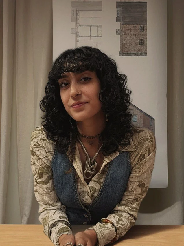 24/Three architectural assistant Rasha wearing a double layeres outfit with warm lighting and a watercolour masterplan in the background