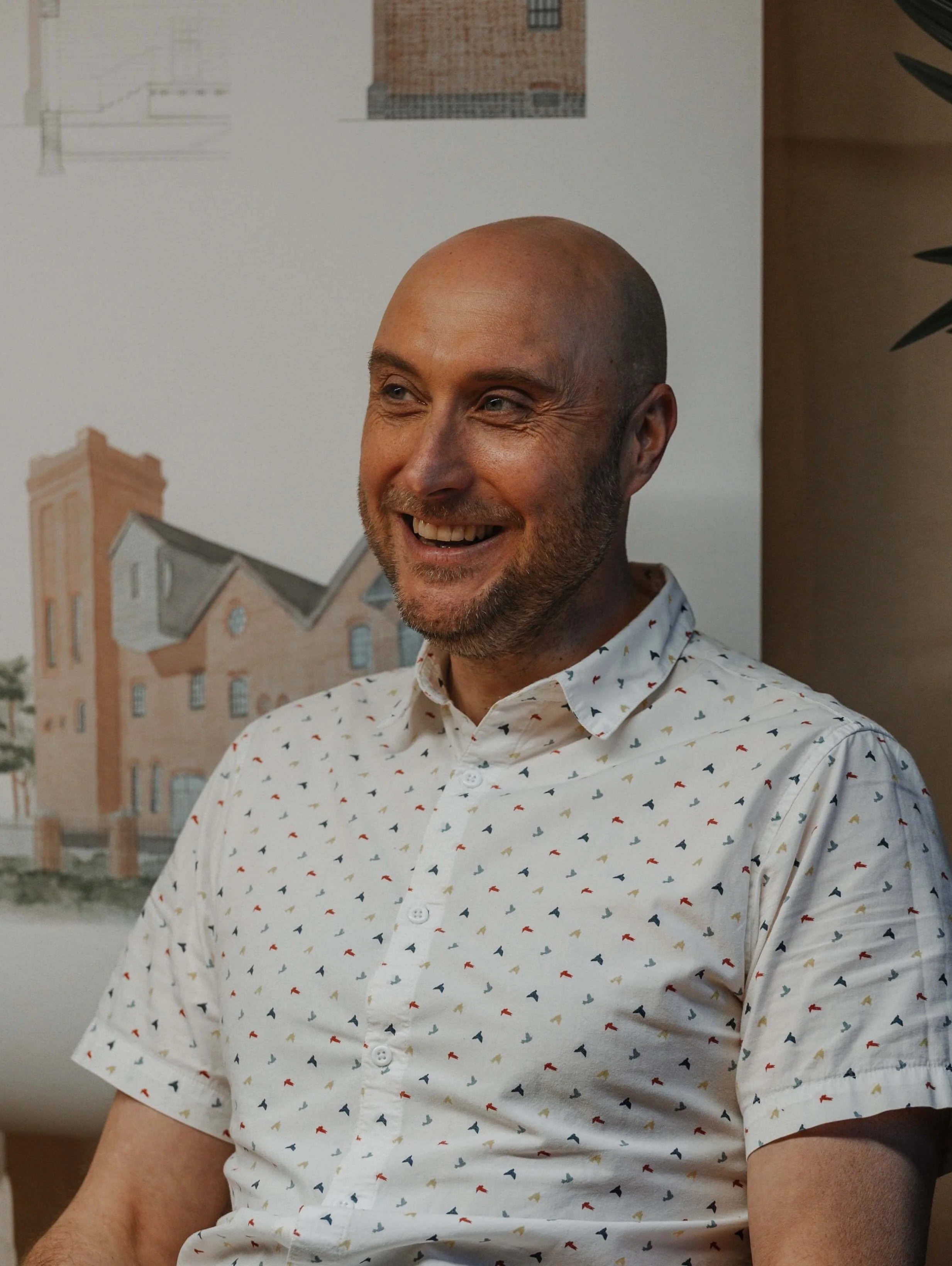 Matt, 24/Three’s Senior Architect Technician, seated in the studio with design plans reflecting sustainable architecture