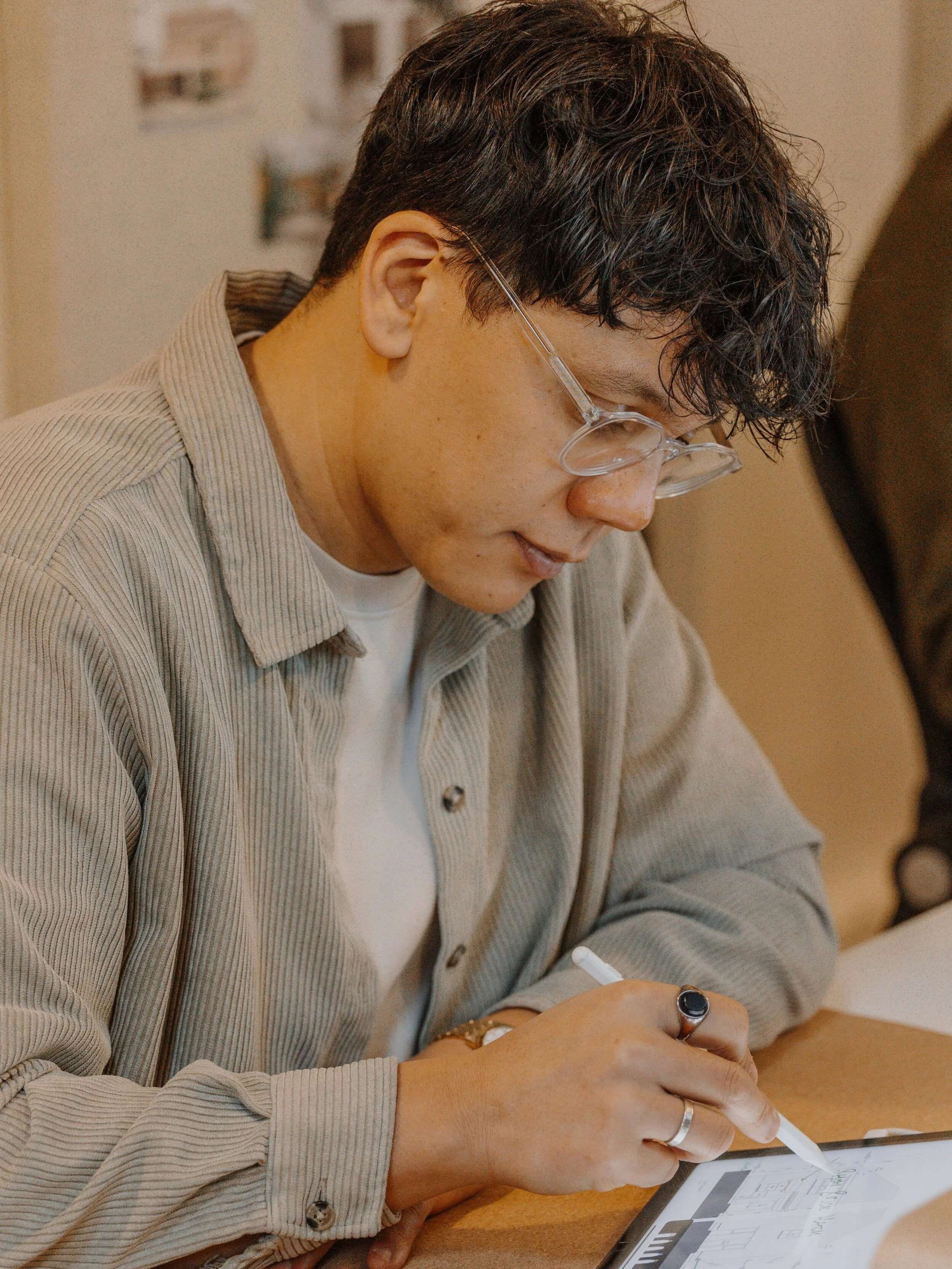 Side profile of Mark Branch, BIM Manager at 24/Three, working at his desk surrounded by digital design software and project drawings.