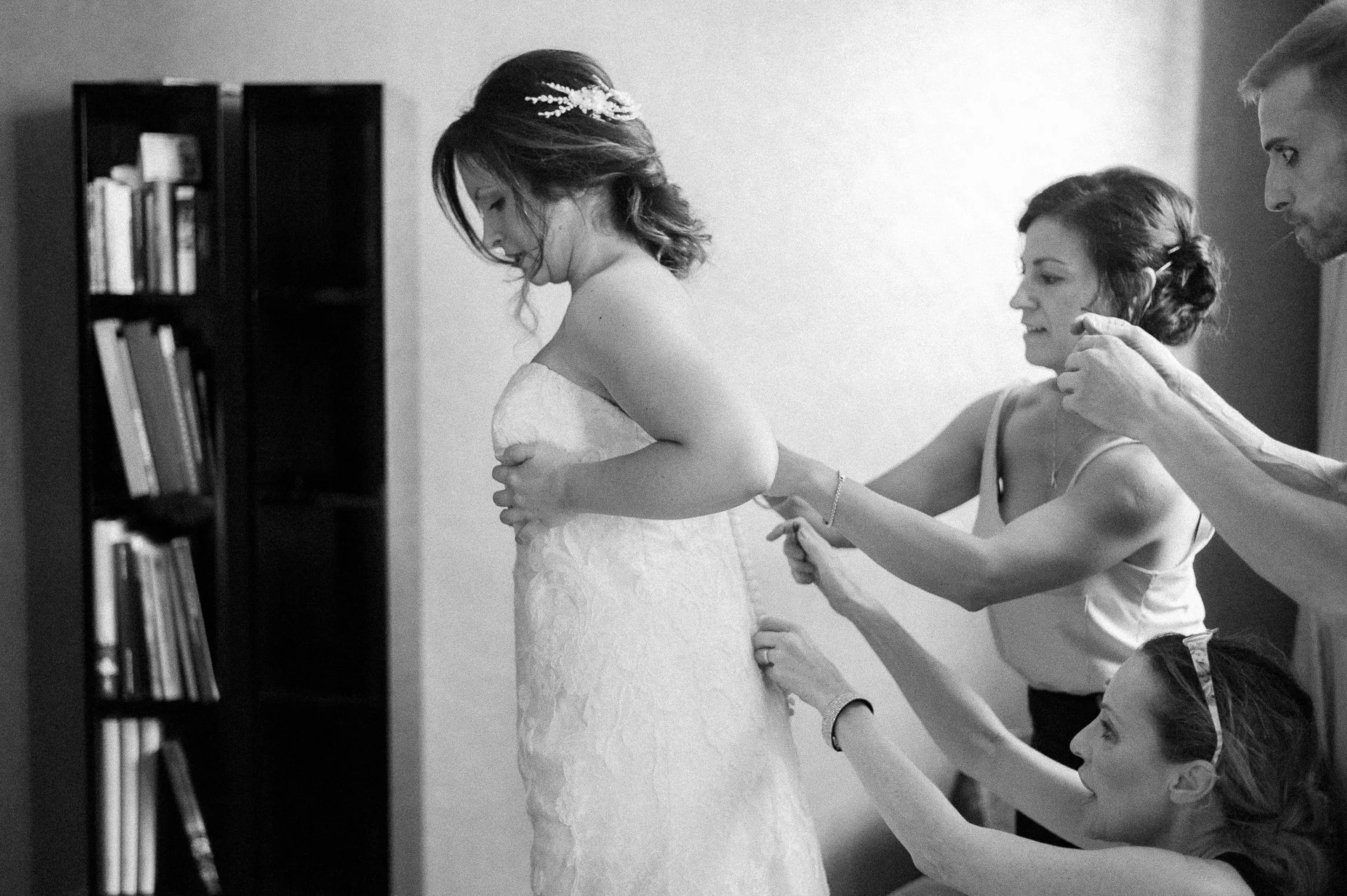 a bride is helped into her wedding dress by three friends at a hotel wedding by thomas bedwin