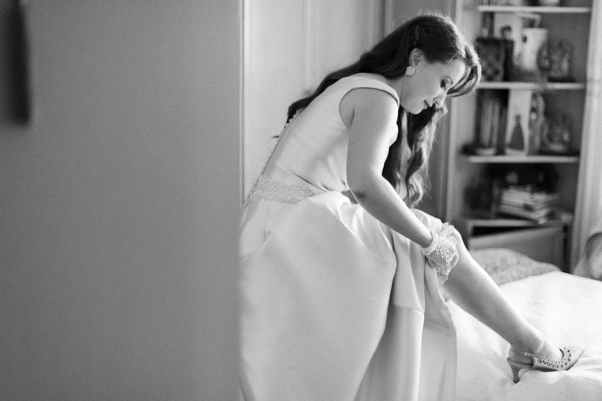 bride puts on garter before rural wedding in farm house by thomas bedwin