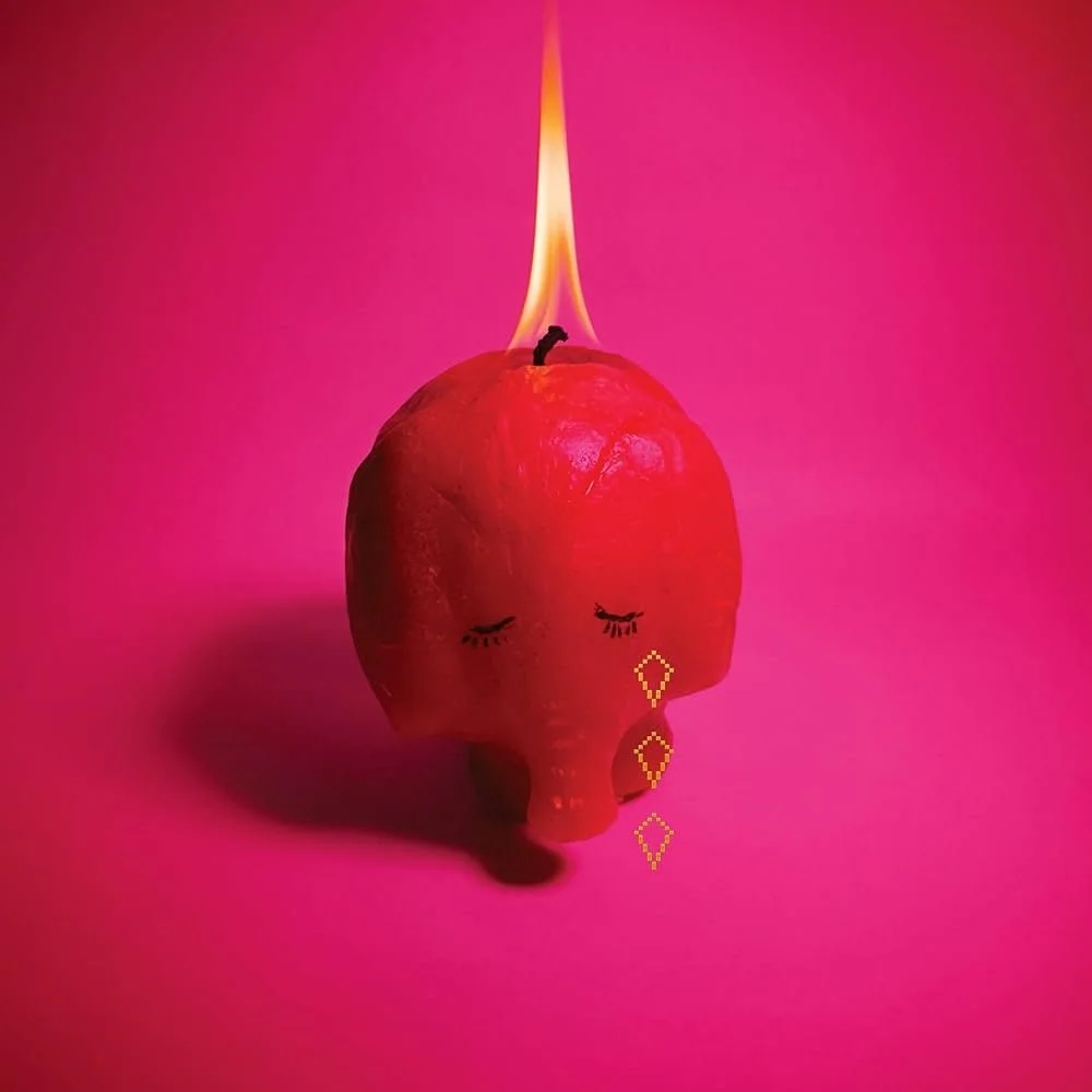 A pink background features a red apple with a flame on top, with drawn closed eyes, long eyelashes, and stylized liquid dripping from its bottom, resembling a crying face.