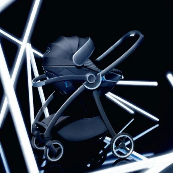A modern baby stroller with a dark design surrounded by illuminated neon light tubes in a dark setting.