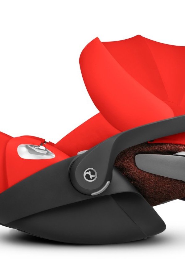 Close-up of a red and black infant car seat with a canopy and adjustable base.