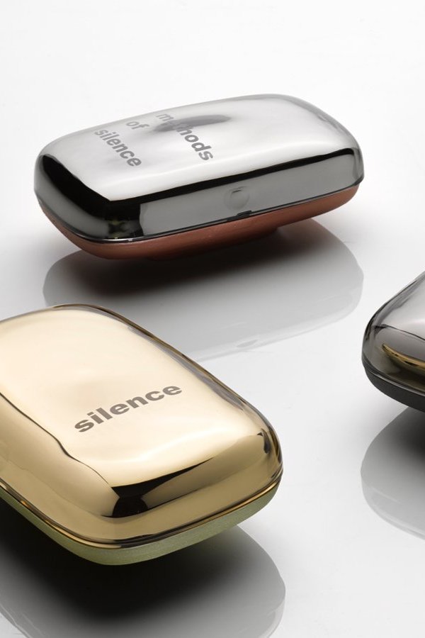 几个带有“silence”字样标签的金属和塑料盒子，放在白色表面上，反射光泽