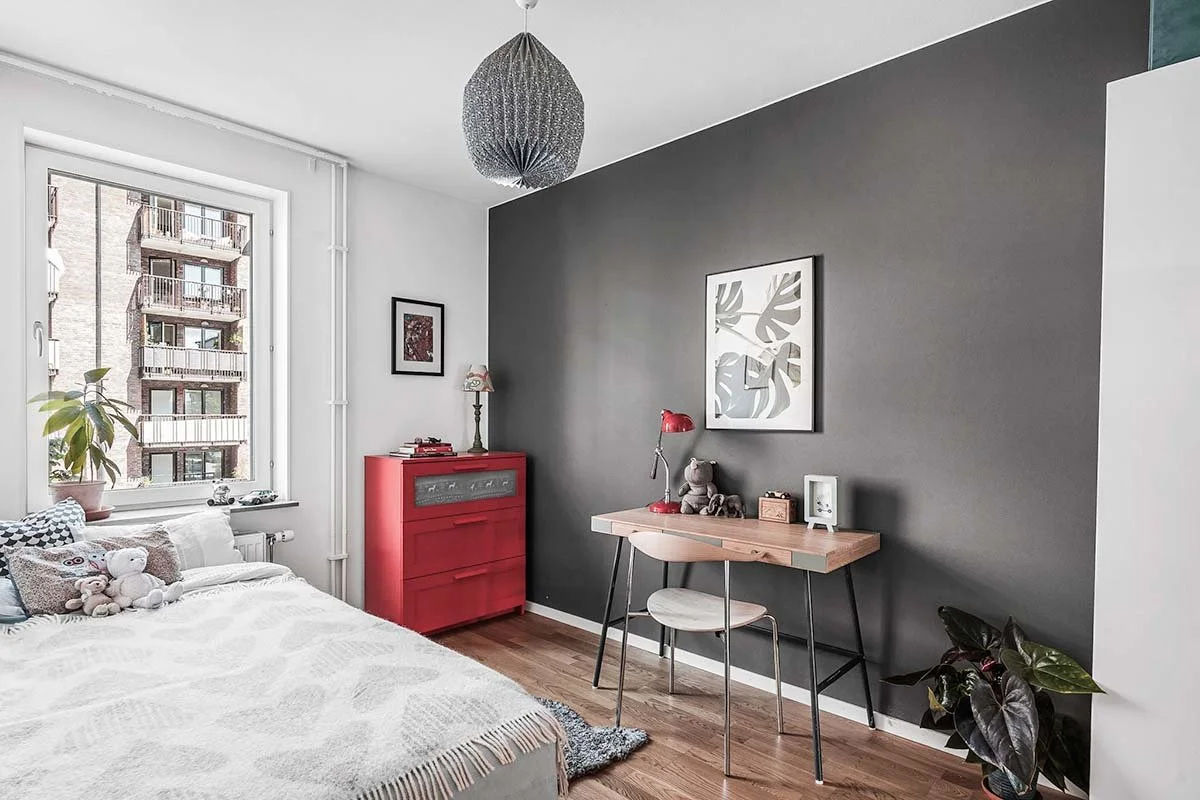 Homestyling Lidingö. Sovrum med röd byrå, säng och tavlor på vägg.
