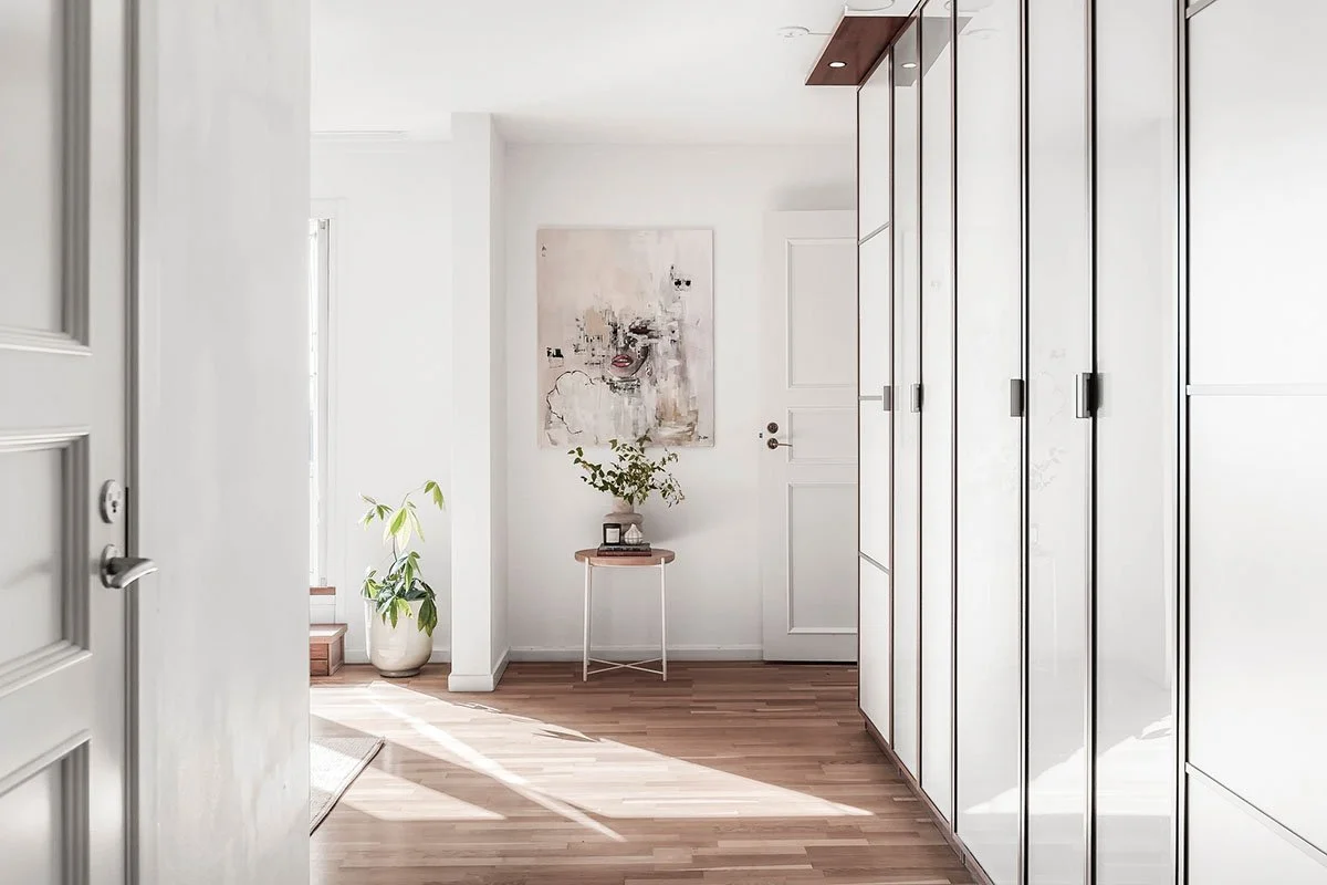 Homestyling av omöblerad lägenhet på Lidingö inför försäljning – ljus hall med konst och utvalda inredningsdetaljer.