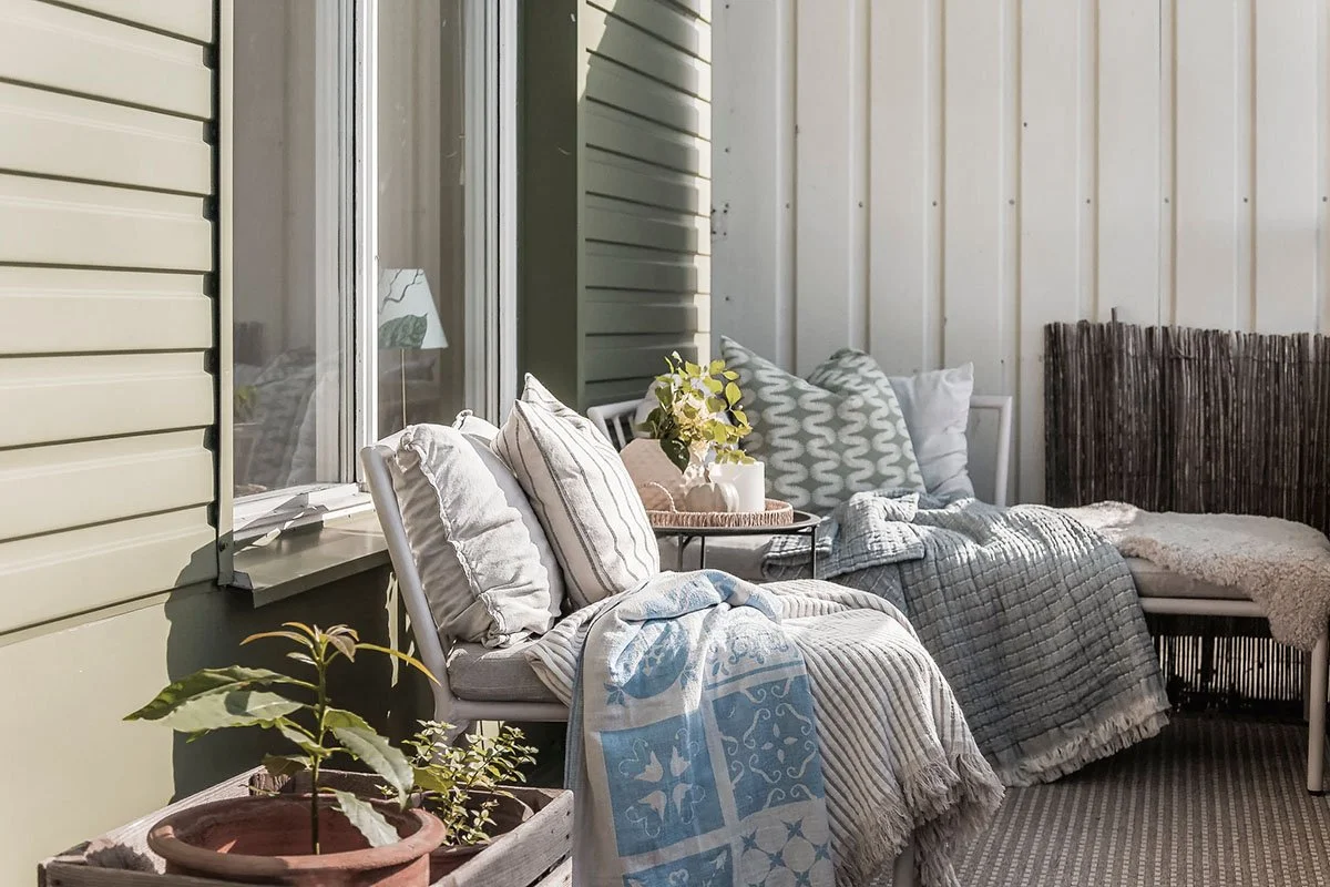 Balkong stylad inför försäljning med textilier, växter och sittplats – homestyling av lägenhet på Lidingö.