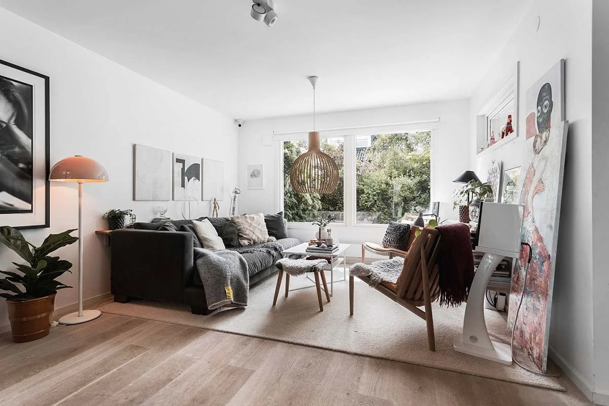 Homestyling Lidingö. Vardagsrum med stora fönster, soffa och modern konst på väggarna.