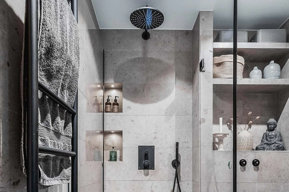 Homestyling Lidingö. Stilrent badrum med dusch, hyllor och dekorativa detaljer.