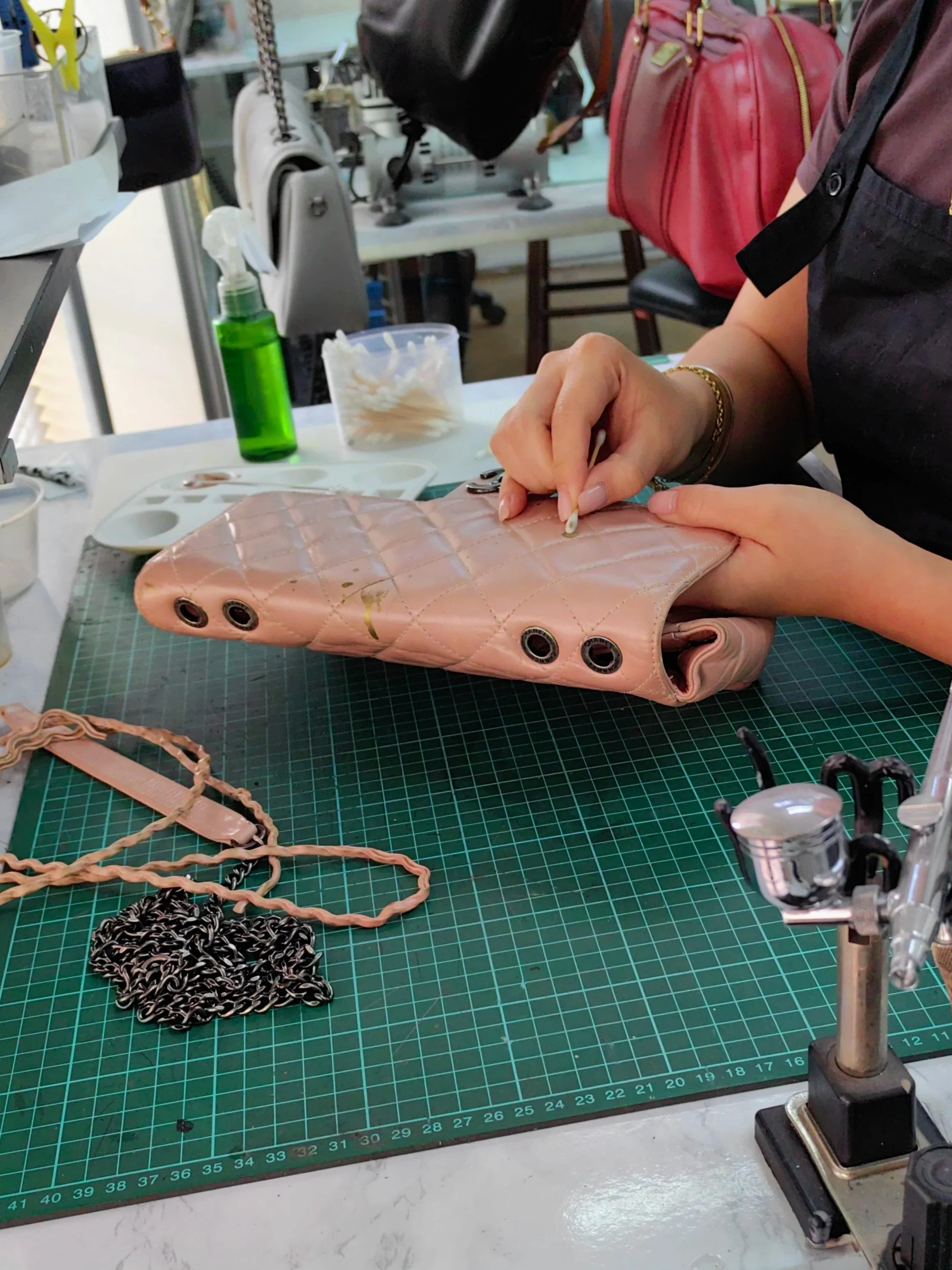 Professional leather restorer hands at work on a Chanel luxury handbag in Leather Biz Plaza Damas studio in Kuala Lumpur, Malaysia