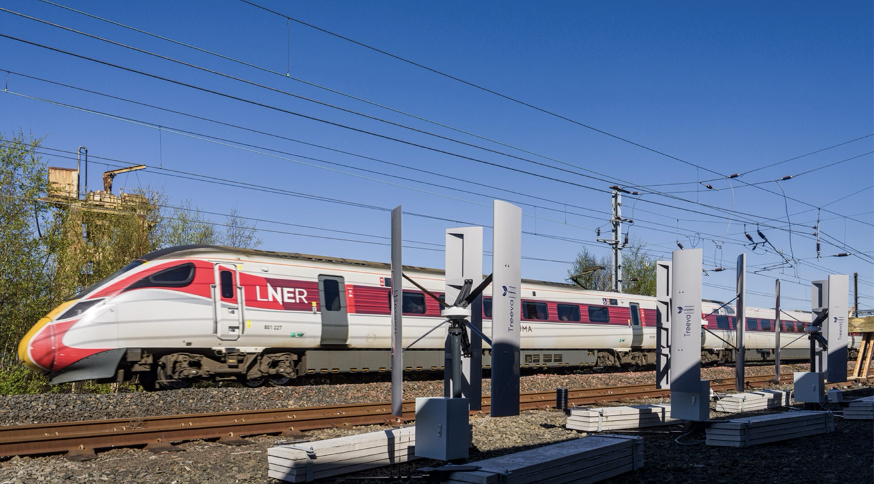 Wind turbines beside railway tracks capture power from passing trains