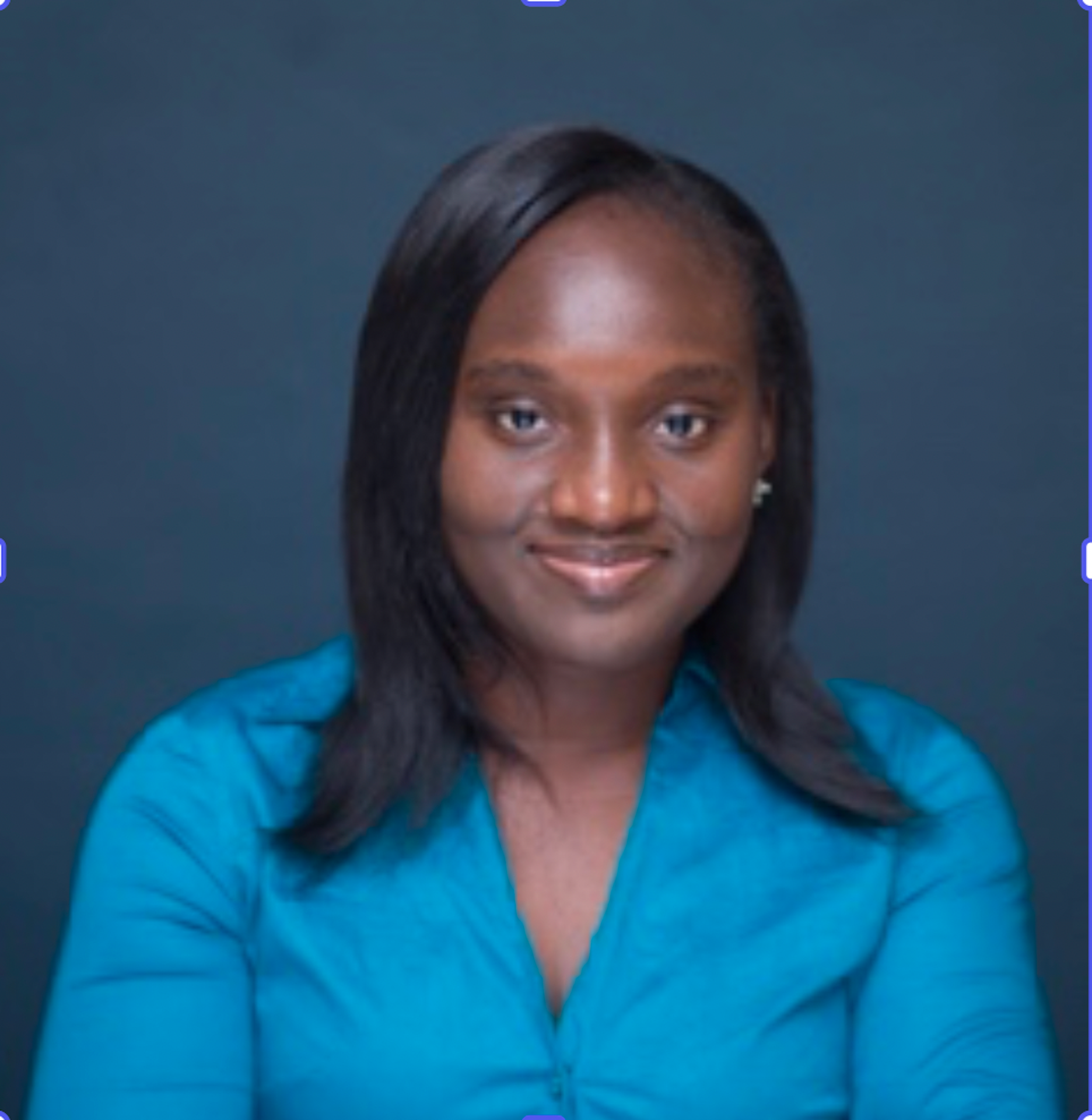 A woman with straight black hair, wearing a blue shirt, smiling against a dark blue background.
