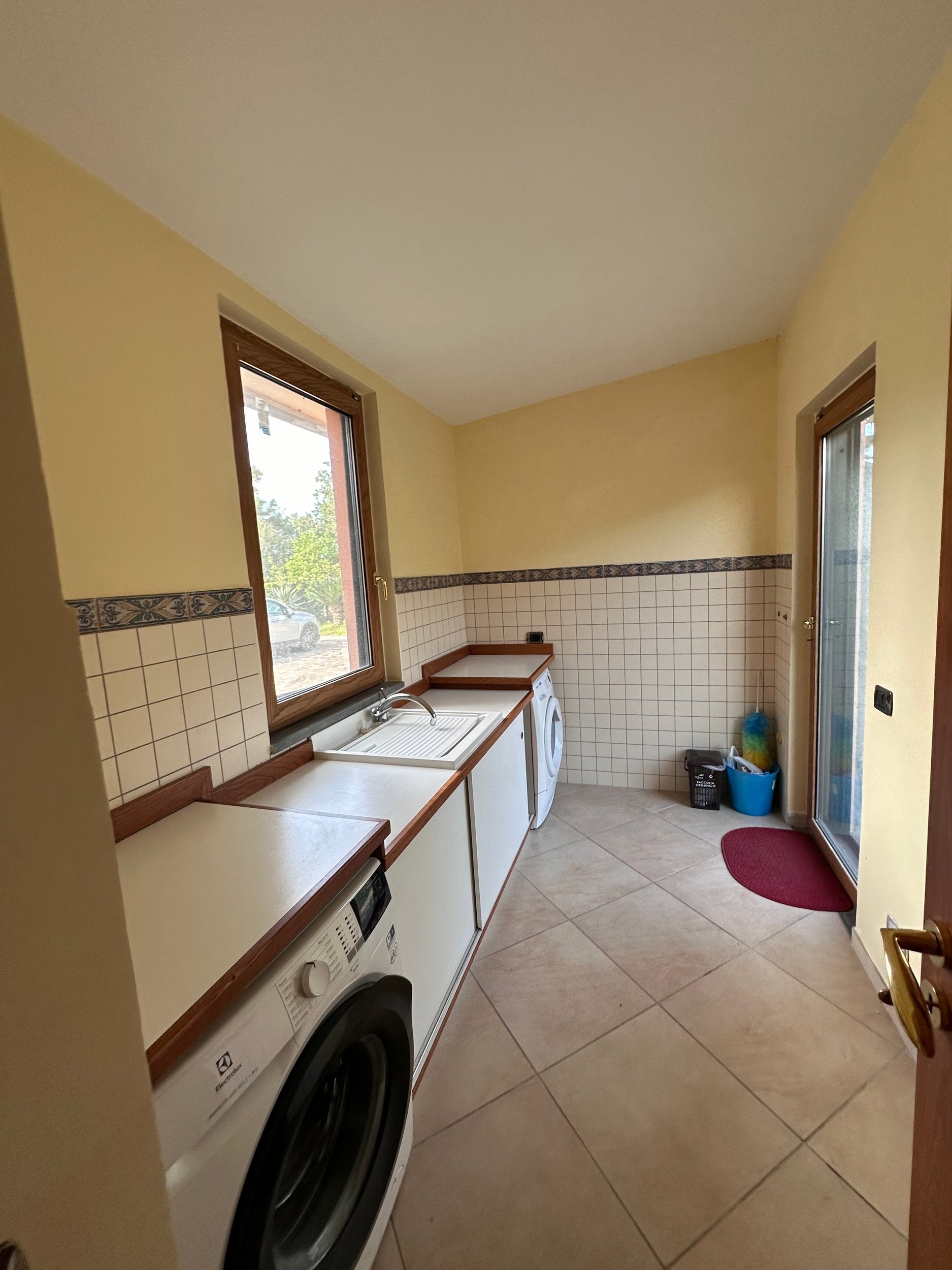 Laundry room with washing machine, dryer, sink, and tile flooring.