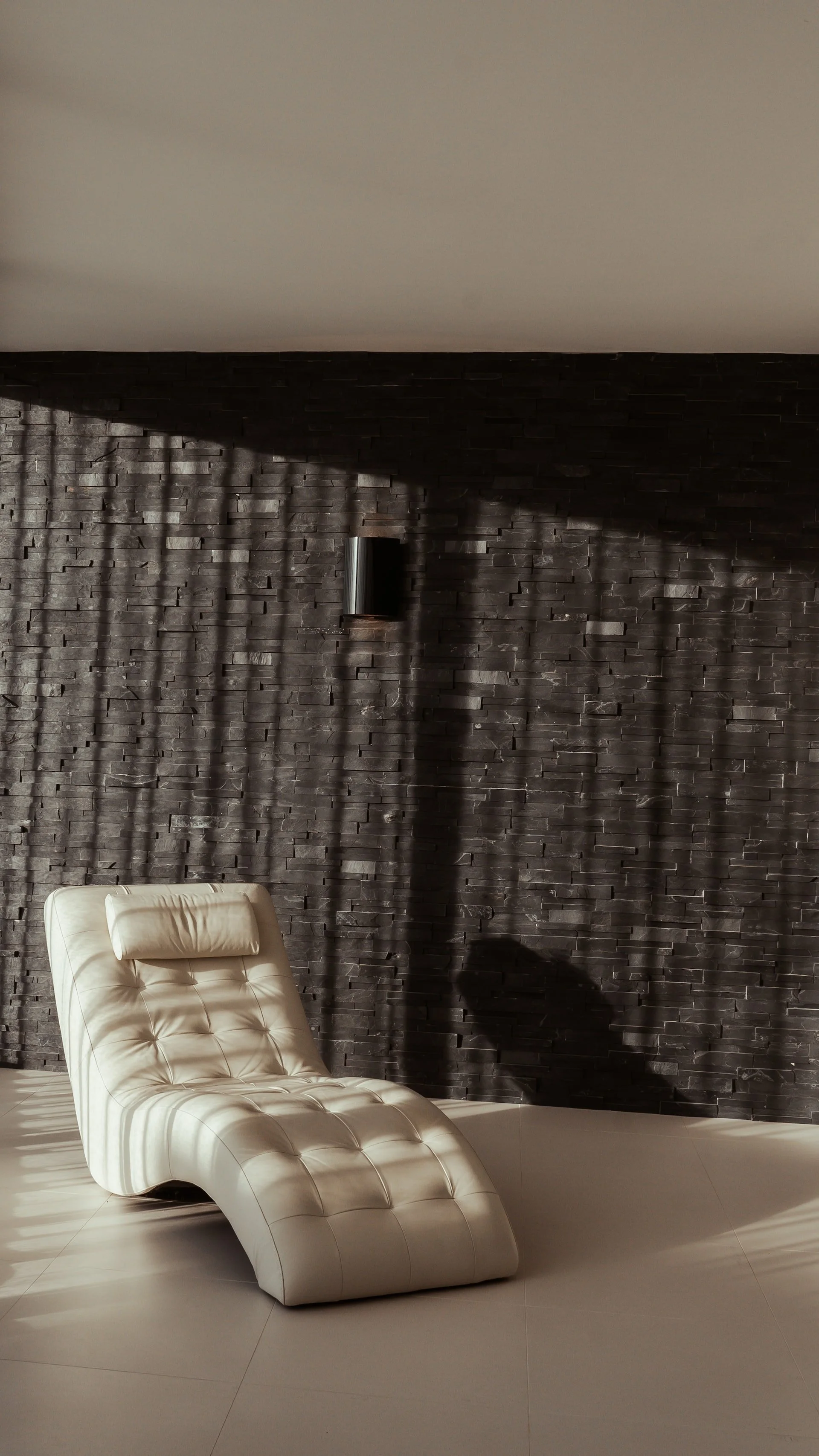 Premium Squarespace Template, Interior Design Squarespace Template, Avelã Creative. Modern interior with a white leather chaise lounge against a dark textured wall