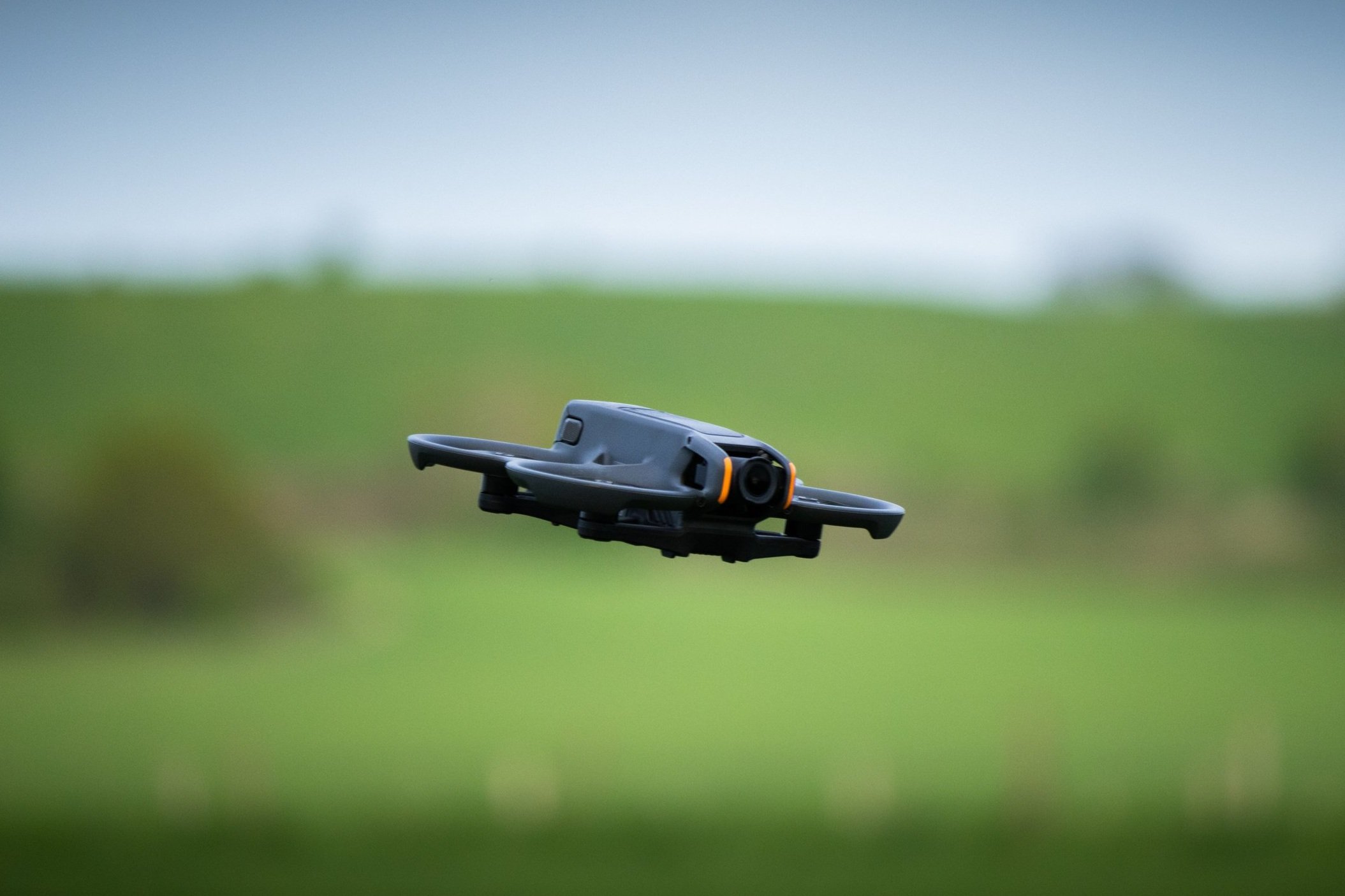 Drone vliegt boven een groene veld, bewolkte hemel op de achtergrond.
