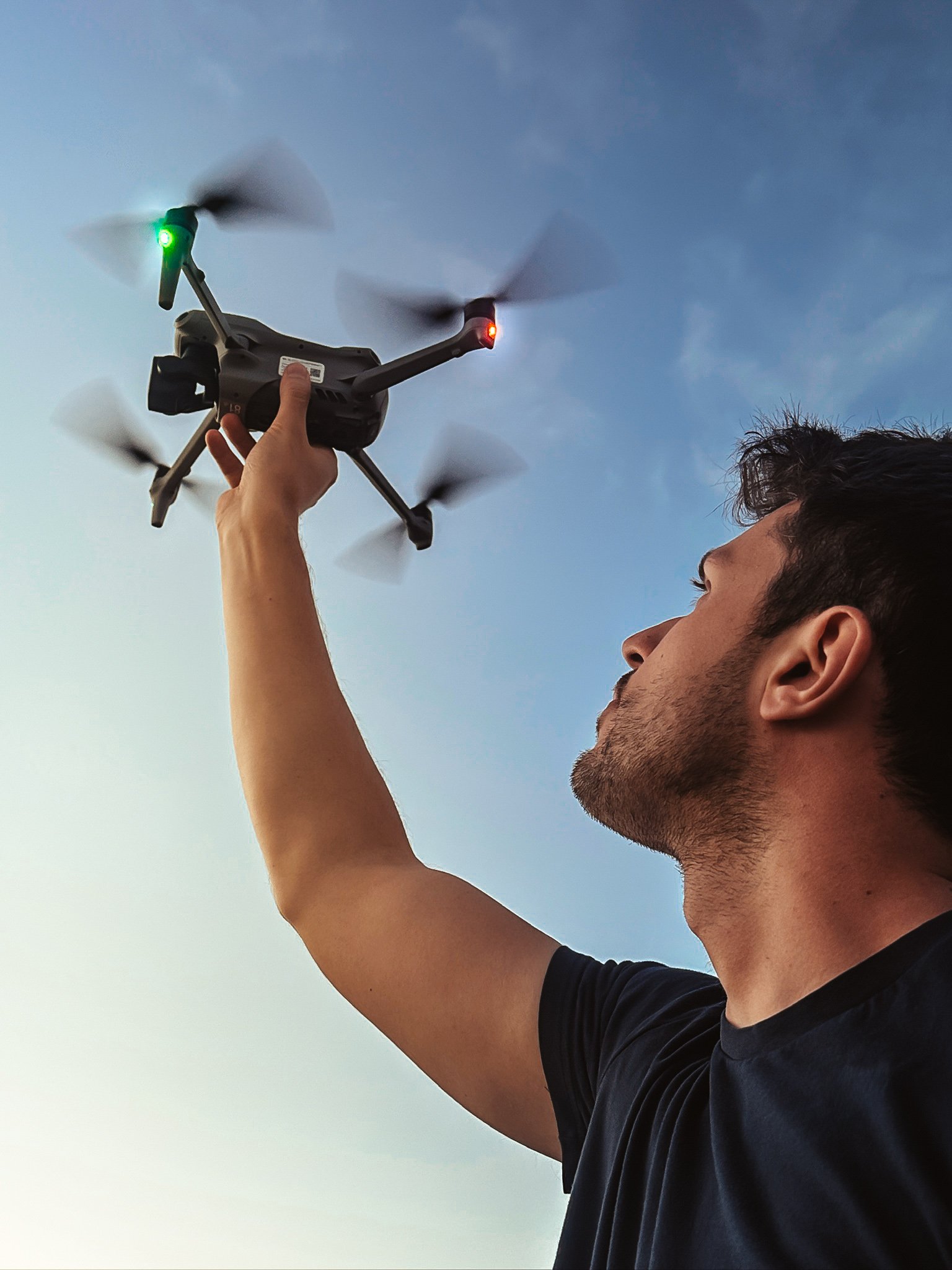 Man die een drone vasthoudt tegen de achtergrond van de blauwe hemel.
