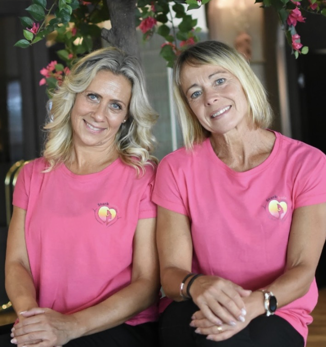 two blonde women in pink t-shirts smiling