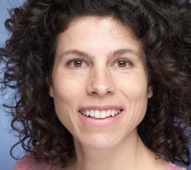 Close-up of a woman with curly dark hair smiling.