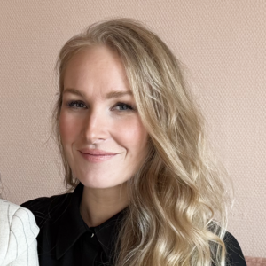 Blonde woman smiling against beige background