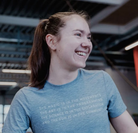 Young woman with brown hair in a ponytail and blue t-shirt smiling