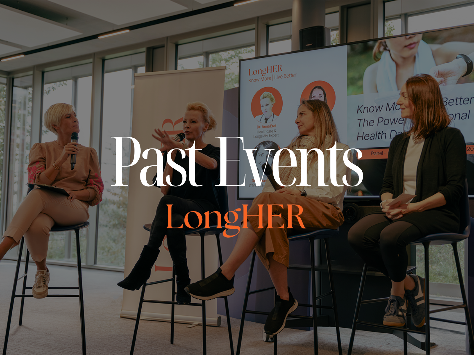 Panoramic view of a city waterfront with colorful historic buildings, a white boat on the water, and a tall church steeple against a blue sky.