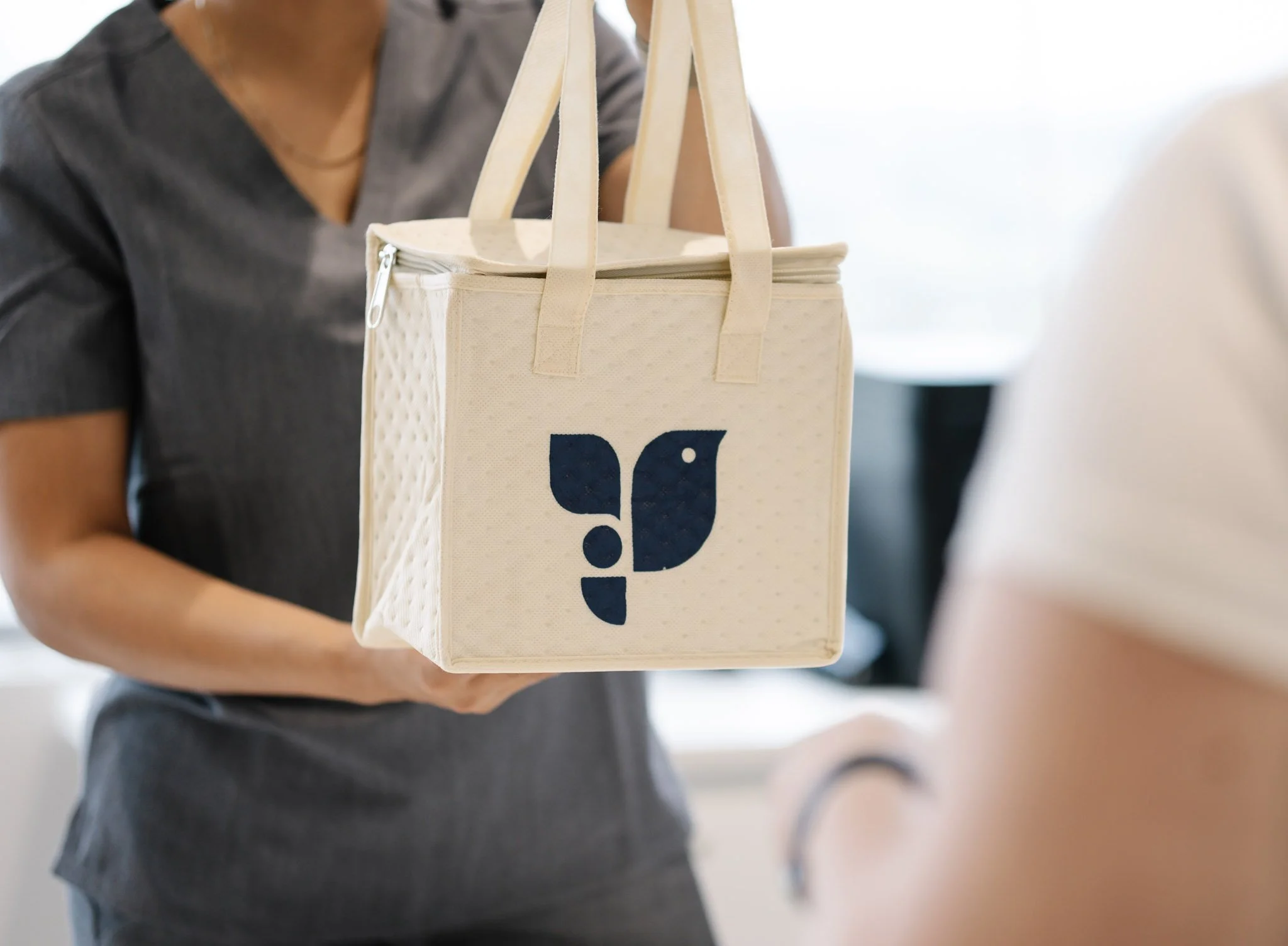 Person holding a white Hannam Fertility medication bag, in an indoor setting.