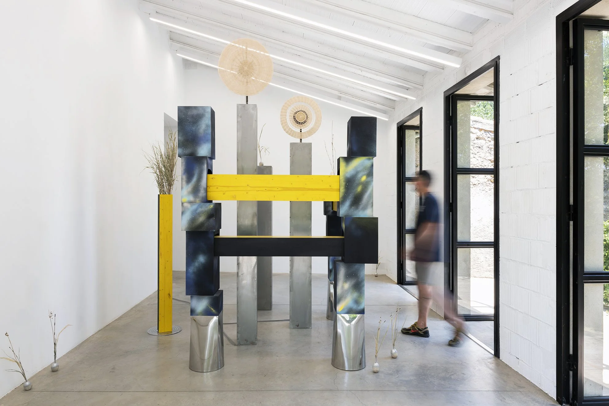 Leah Dixon. TARTAN TARTANA: The Girl Who Invented The Wheel IV, 2026. 
Site specific sculpture (indoor). Wood, steel, paint, enamel, woven basket wheels, rotary motors, molded sawdust and resin clay onions, natural rattan, esparto grass, horsetail re