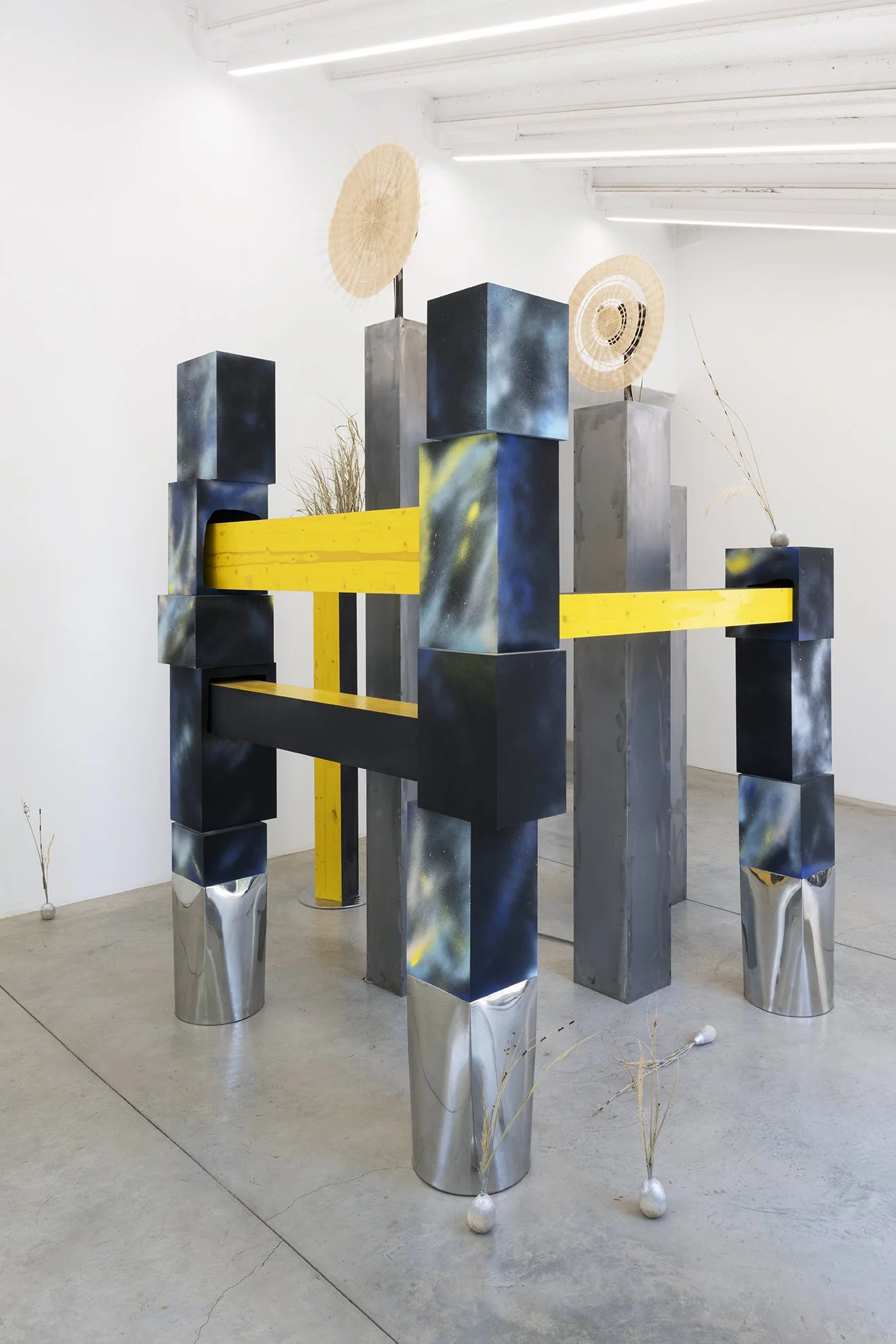 Leah Dixon. TARTAN TARTANA: The Girl Who Invented The Wheel IV, 2026. 
Site specific sculpture (indoor). Wood, steel, paint, enamel, woven basket wheels, rotary motors, molded sawdust and resin clay onions, natural rattan, esparto grass, horsetail re