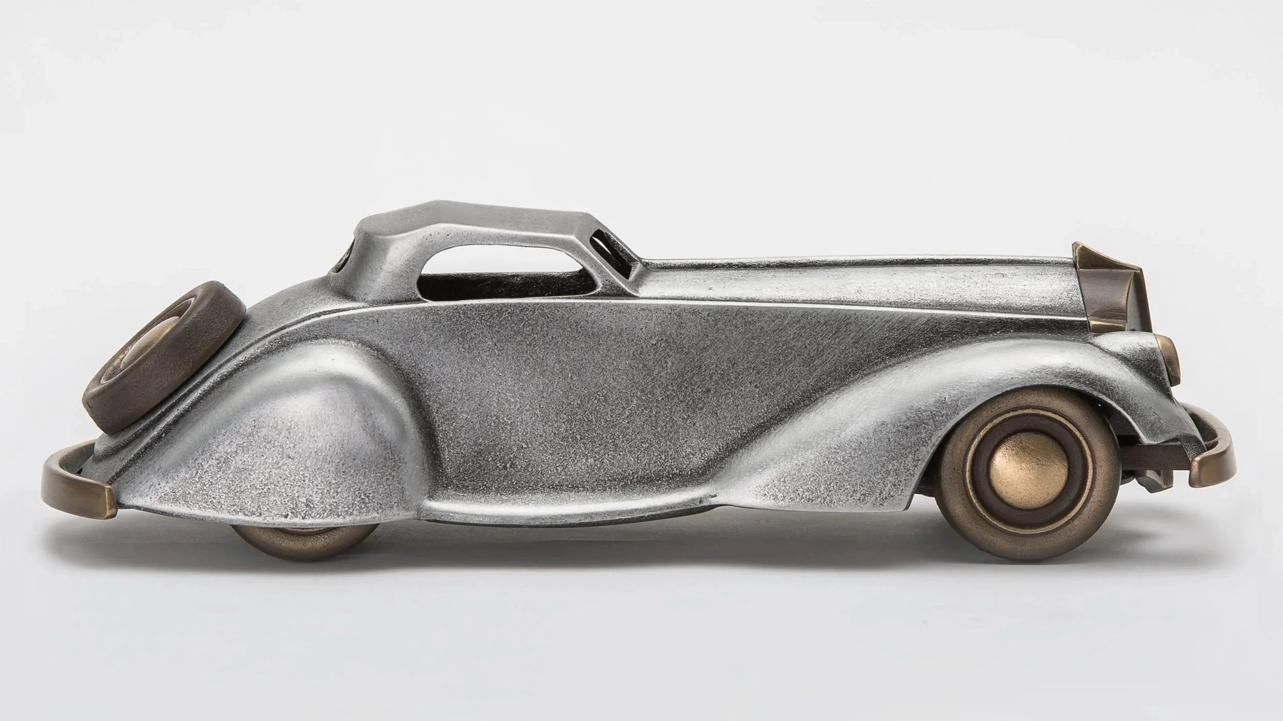 Close-up of a vintage silver toy car with brown wheels against a white background.