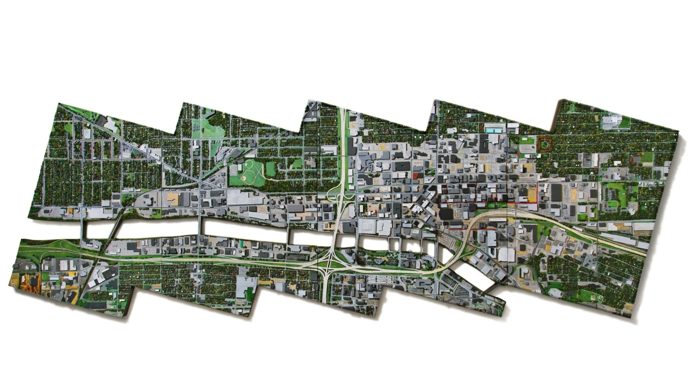 A jigsaw puzzle with an aerial map of a city, showing streets, parks, and buildings, assembled partially on a white background.