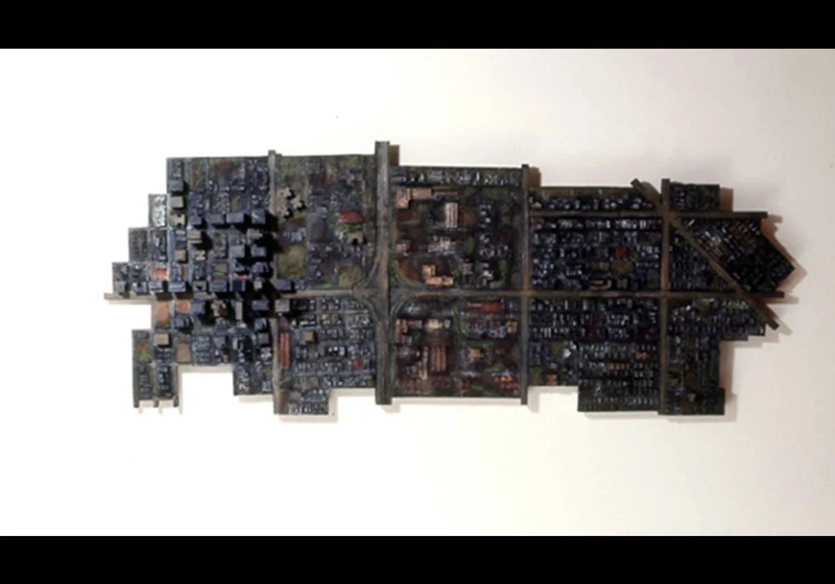 A wall art piece designed as a city skyline, made of assembled miniature model buildings and structures on a white background.