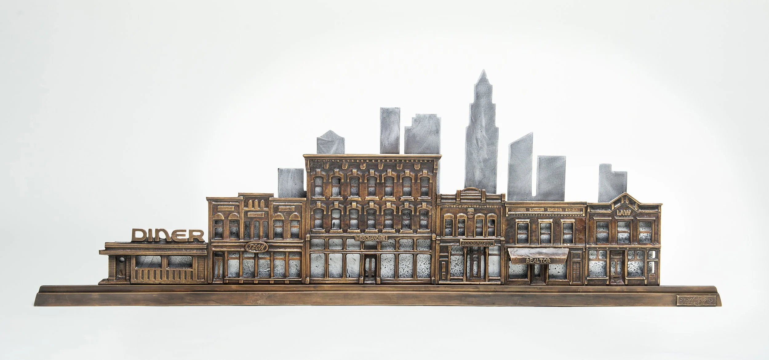 A metallic cityscape sculpture with buildings labeled as 'Diner,' 'Tech,' 'Merchandise,' 'Accountant,' 'Realtor,' and 'Law,' set against a plain white background.