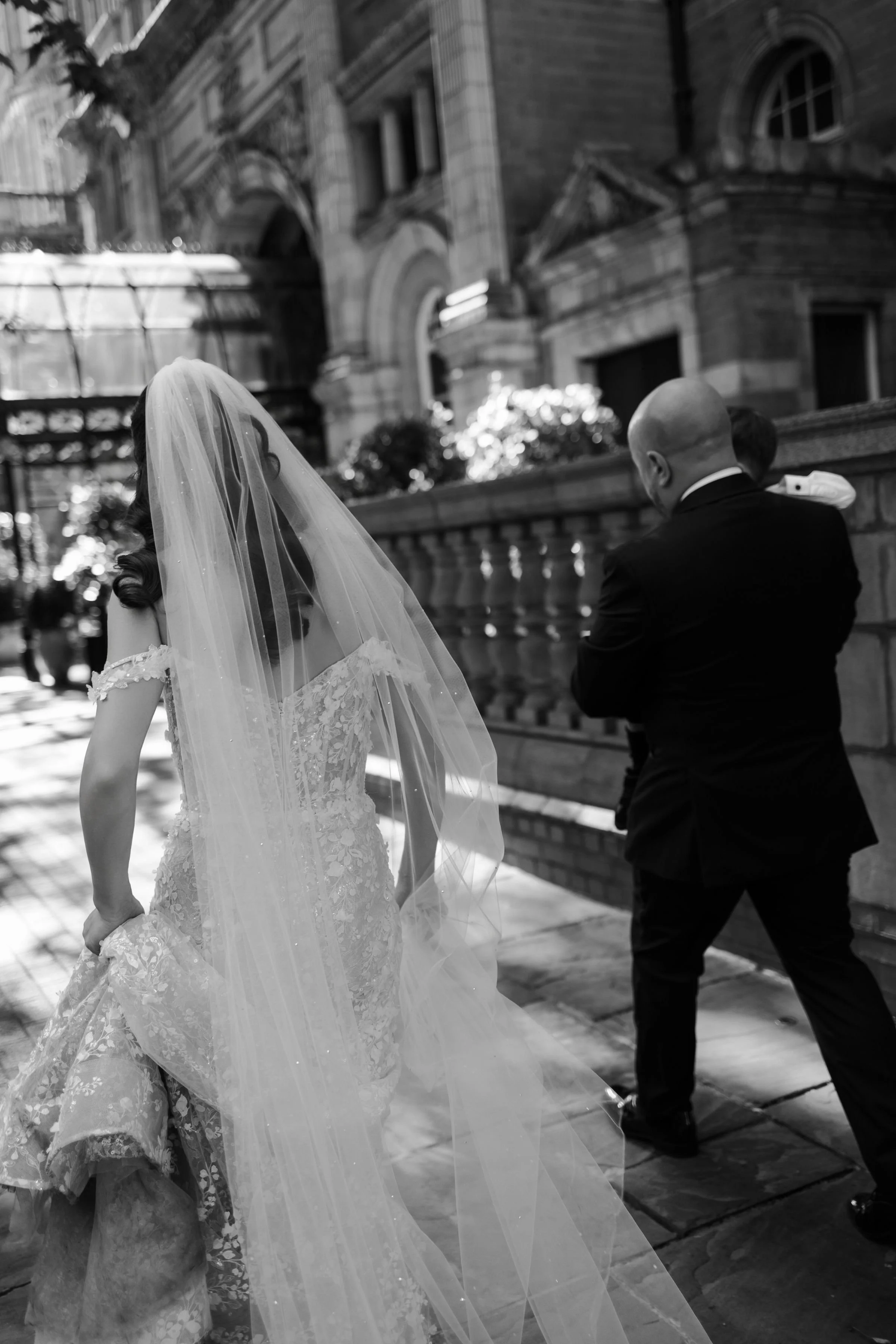 Bride walking through London in her wedding dress and long veil.