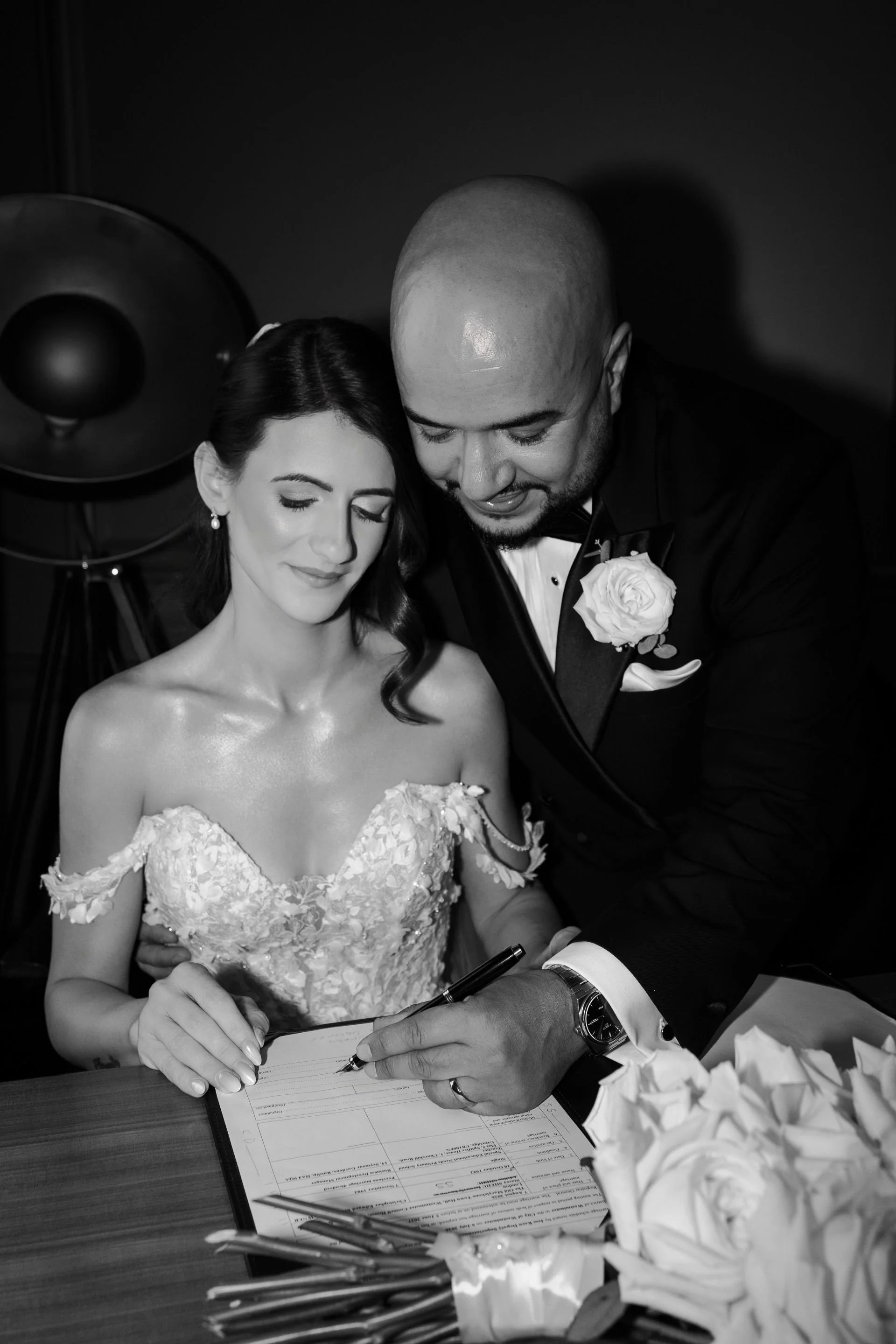 Black and white photo of a bride and groom signing their wedding register.