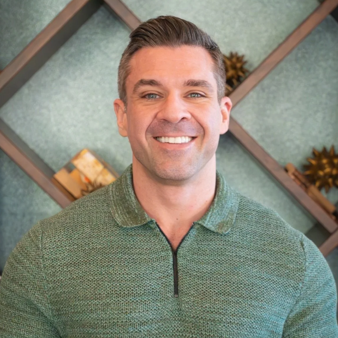Mark Neuterman. AI VISIBILITY. A smiling man with short brown hair and blue eyes, dressed in a navy blazer and blue shirt, leaning against a brick wall.